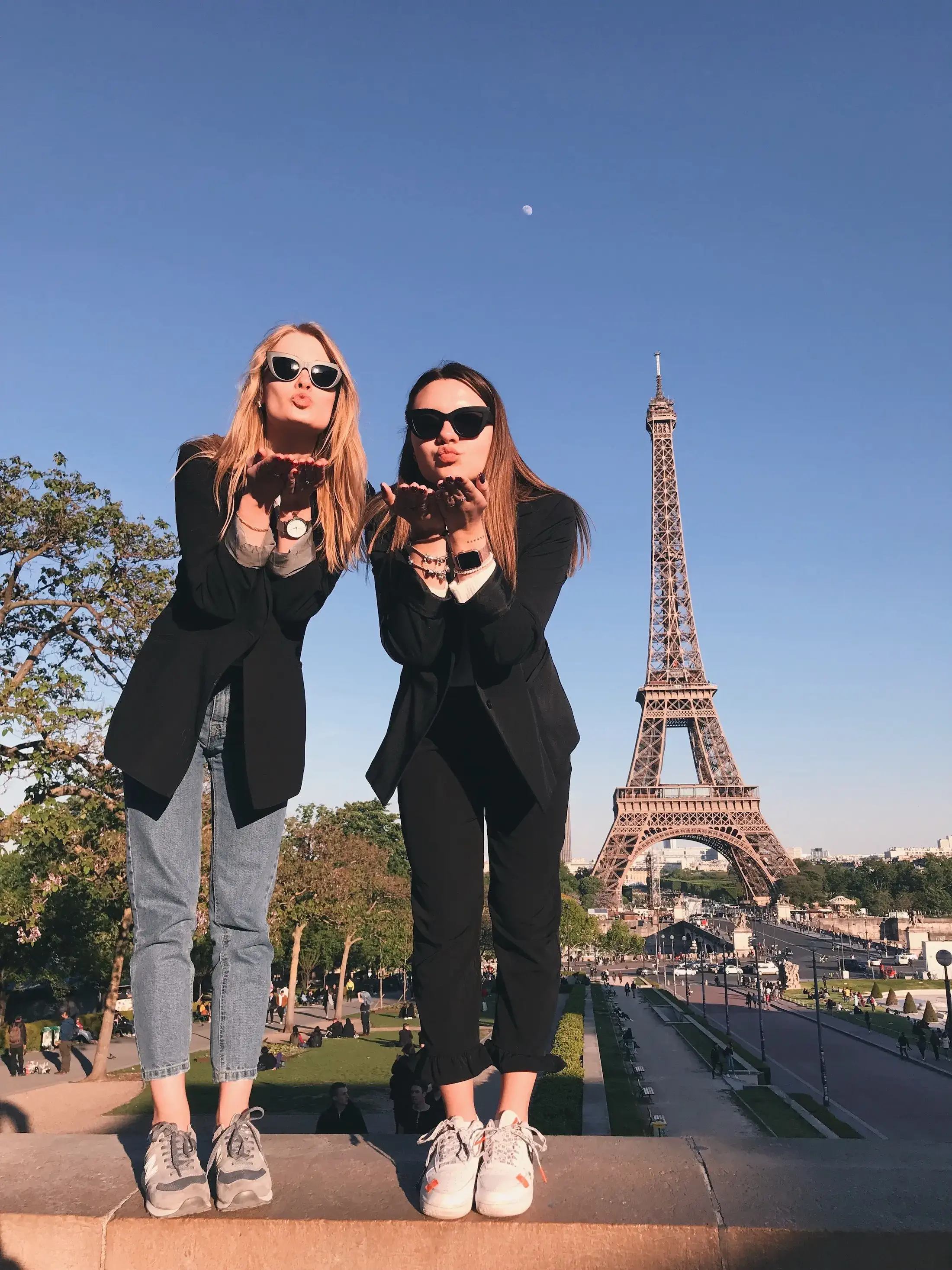 two women blowing kisses in fron tof Eiffel Tower